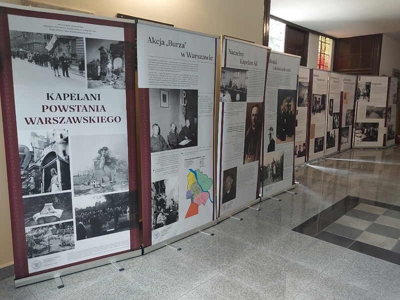 Fotografia przedstawia wewnętrzną ekspozycję pod nazwą Kapelani Powstania Warszawskiego. We wnętrzu kościoła rozstawionych jest rollapów ze zdjęciami i tekstem.