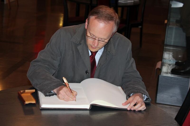 Prezes IPN dokonuje wpisu w księdze pamiątkowej COSSW