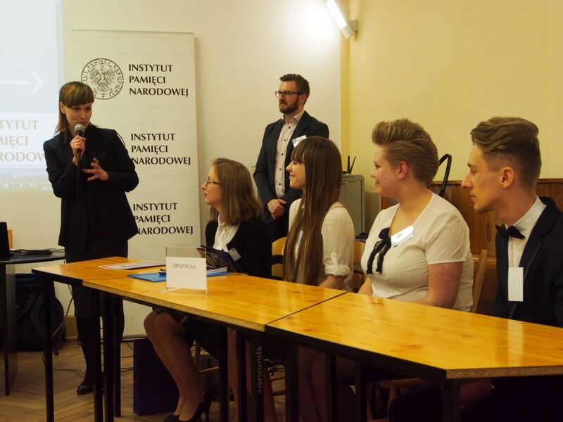 Magdalena Zapolska-Downar (OBEP IPN Łódź) zamyka I Regionalny Turniej Debat Oksfordzkich. Obok stoi dr Krzysztof Latocha (OBEP IPN w Łodzi). Siedzą laureaci Turnieju